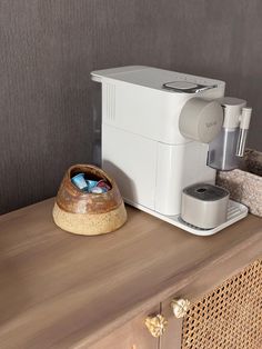 a white coffee maker sitting on top of a wooden table next to a cup holder