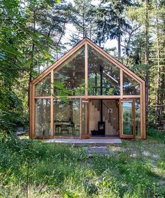 a small cabin in the middle of a forest with lots of grass and trees around it