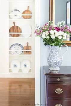 a vase filled with flowers sitting on top of a wooden dresser