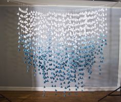 blue and white paper butterflies are hanging from the ceiling in front of a photo backdrop