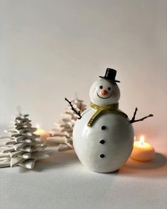 a snowman with a hat and scarf next to candles