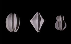 three paper sculptures in the dark with one being folded up to look like an origami