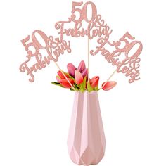 a pink vase filled with flowers on top of a white table next to a sign that says 50 fabulous birthday