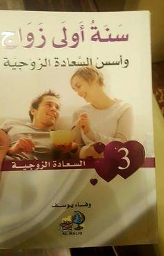 a person holding up a book with arabic writing on the front and back cover, which features an image of a man and woman in bed