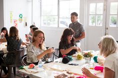 a group of people sitting around a table with cake on it and one woman holding a cell phone