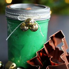 a jar filled with green liquid next to some gold bells