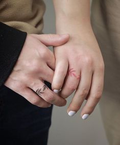 two people are holding hands with tattoos on their fingers and one has a flower tattoo on her left hand