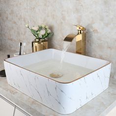 a white sink sitting on top of a counter next to a gold faucet