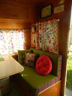 a green couch sitting in the corner of a room next to a table and window