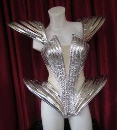 a white mannequin with silver metallic wings on it's chest and arms