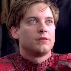 a close up of a person wearing a spiderman shirt and looking into the distance