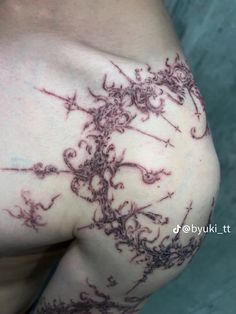 the back of a woman's shoulder with tattoos on it and an intricate design