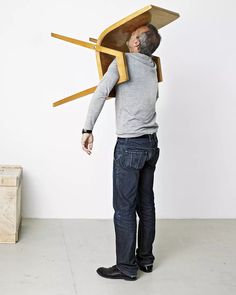 a man is standing in front of a boat shaped chair that he has built into the wall