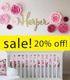 a white crib with pink flowers on the wall and a yellow sign that says harper sale 20 % off