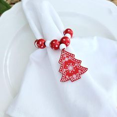 a white plate topped with a red and white christmas tree napkin holder on top of a table