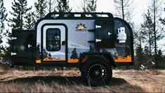 an off road camper parked in the middle of a field with trees around it