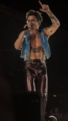 a shirtless man on stage with his hands in the air and one hand up