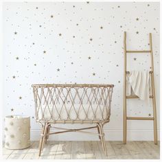 a baby crib next to a white wall with gray dots on it and a ladder