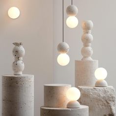 three white vases sitting next to each other on top of cement pillars with lights hanging from them