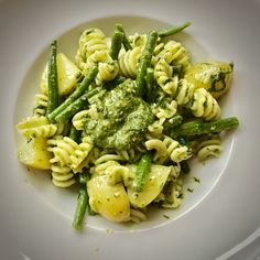 pasta with asparagus and pesto sauce on a white plate, ready to be eaten