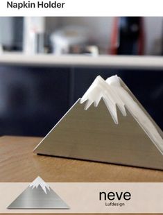 a metal triangle sitting on top of a wooden table next to a white mountain logo