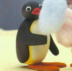 a stuffed penguin is standing next to another toy penguin