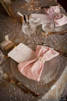 the table is set with pink napkins and place settings for an elegant dinner party