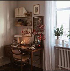 a desk with candles and flowers on it in front of a window, next to a radiator