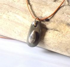 This pendant is made with a coastal stone, either ocean or river. The stone is not tumbled or shaped but is in its natural form, except for the drilled hole. Therefore, the stone/rock will have its natural "imperfections" just as nature made it. This adds character and uniqueness to the piece. They make a perfect gift for rockhounds, yoga\ Zen lovers, surfers or just anyone who loves the beauty of nature. Two stones are used to create this pendant. The small stone is a teardrop shape with interesting soft coloration. The entire piece is coated with a high gloss sealer to give it a nice sheen and protect the design. Pendant has a metal split ring and hangs on an adjustable wax cotton cord with pull apart clasp.  To adjust the length of the cord: 1. pull  open the clasp; 2. push knot through Natural Rock Necklace, Rock Necklace, Zen Style, Natural Form, Natural Rock, Pull Apart, Natural Forms, Beach Lovers, Split Ring