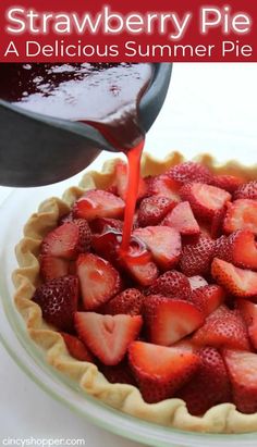 someone pouring syrup onto a pie crust filled with strawberries