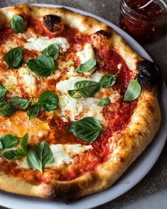 a pizza with basil leaves on it sitting on a plate