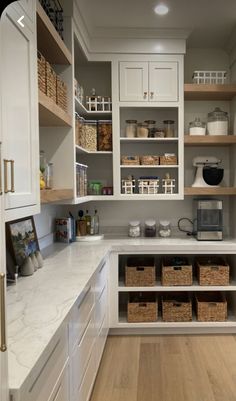 a kitchen filled with lots of white cupboards and shelves next to a counter top