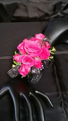 a bouquet of pink roses sitting on top of a black cloth covered table with two hands