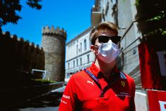 a man wearing a face mask standing in front of an old castle with sunglasses on