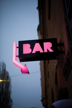 a neon bar sign hanging from the side of a building