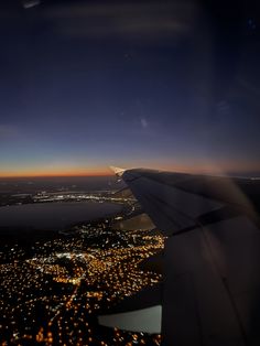 an airplane wing flying over a city at night