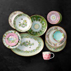 a table topped with plates and cups filled with different colored designs on it's sides