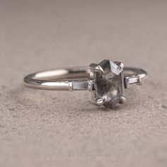 a close up of a ring with a stone in the middle and two baguettes on each side