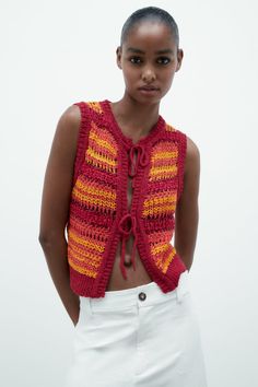 a young woman wearing a red and yellow knitted vest with stripes on the back