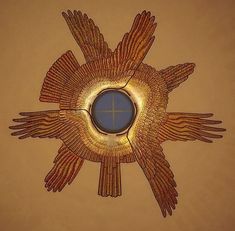 a decorative mirror hanging on the side of a wall next to a cross and wings