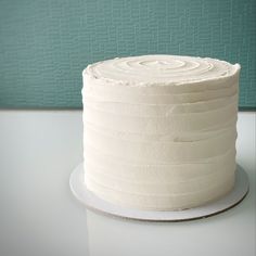 a white frosted cake sitting on top of a table next to a green wall