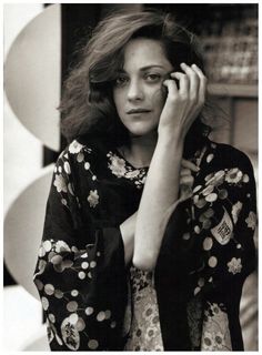 a black and white photo of a woman holding her hand to her face while talking on the phone