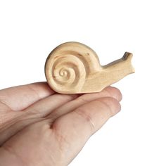 a hand holding a small wooden snail toy