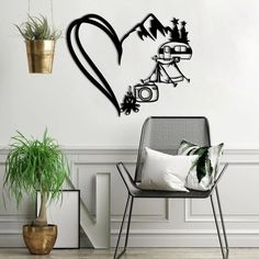 a black heart shaped wall sticker in the corner of a room with a chair and potted plant