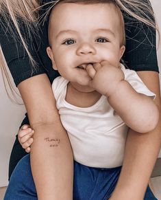 a woman holding a baby in her arms with the words mommy on it's arm