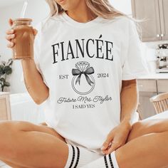 a woman sitting on the floor holding a drink in her hand and wearing a t - shirt that says france