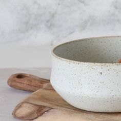 a white bowl sitting on top of a wooden cutting board