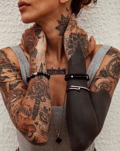 a woman with lots of tattoos on her arms and chest, holding hands behind her neck