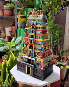 a colorful model of a building on top of a table next to potted plants