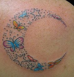 a woman's back with butterflies and a crescent tattoo